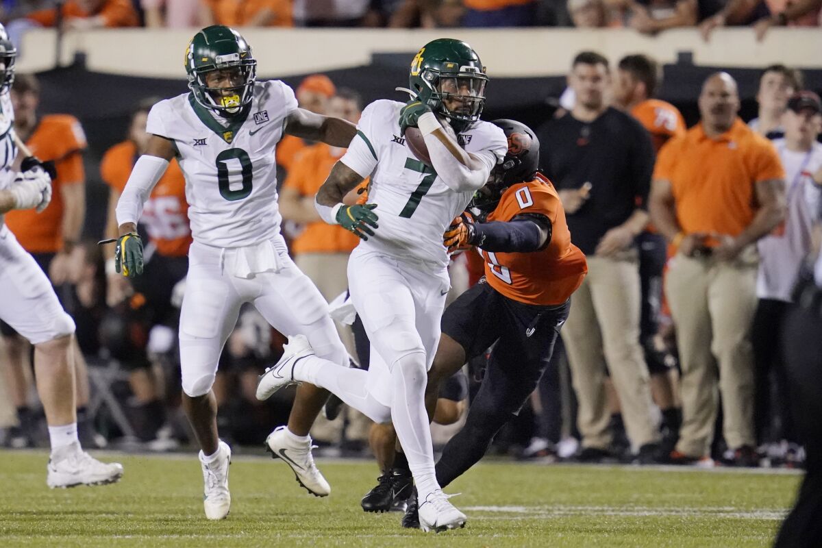 Baylor running back Abram Smith (7) carries past Oklahoma State cornerback Christian Holmes (0) on a 55-yard touchdown run in the second half of an NCAA college football game, Saturday, Oct. 2, 2021, in Stillwater, Okla. (AP Photo/Sue Ogrocki)
