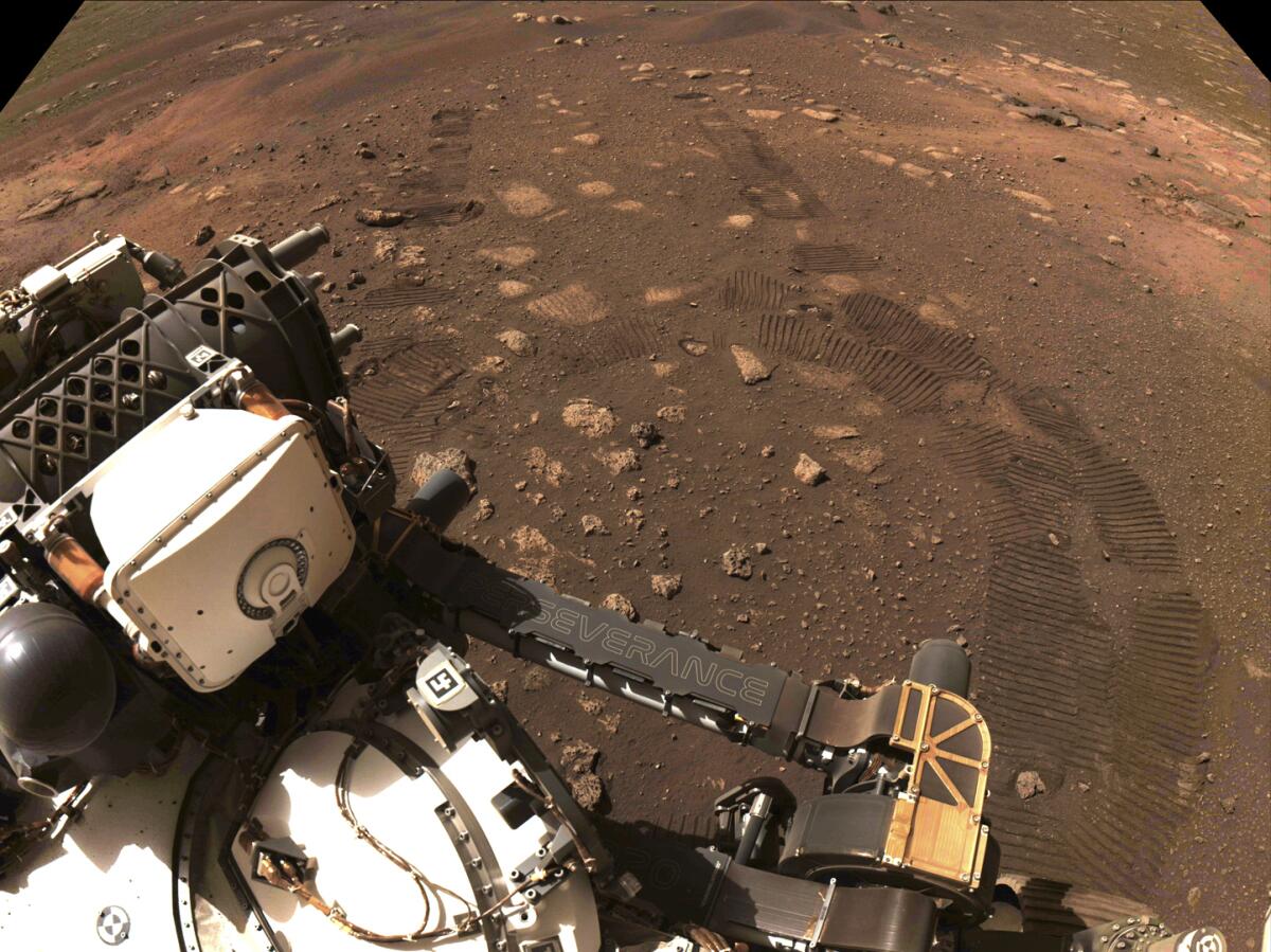 A robotic rover on a rocky, reddish surface 