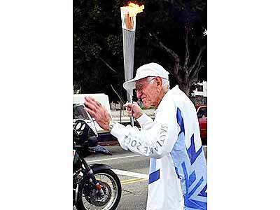 About to take off with the Olympic Torch is 85-year-old Louis Zamperini at the intersection of 27th and Western, Tuesday afternoon in Los Angeles.