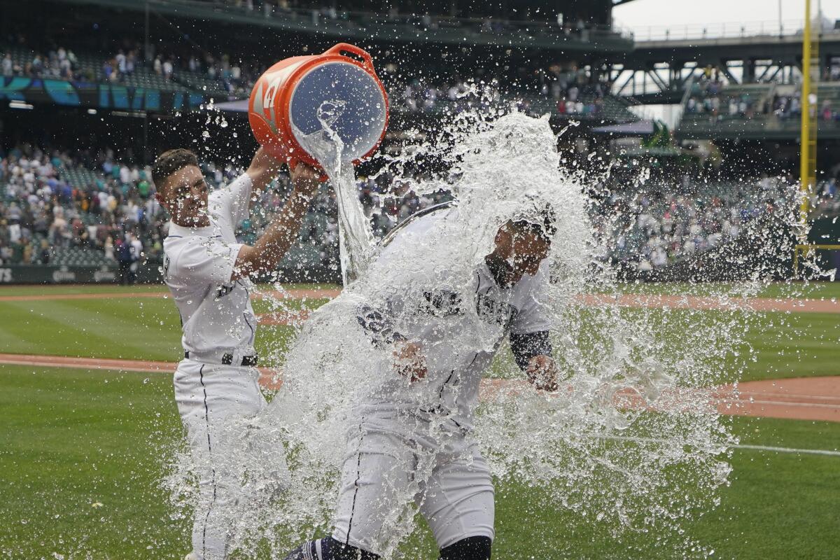 Seattle Mariners' Abraham Toro, right, has water dumped onto him by Adam Frazier, left, after Toro hit a single to score Marcus Wilson with the winning run during the ninth inning of the team's baseball game against the Oakland Athletics, Saturday, July 2, 2022, in Seattle. The Mariners won 2-1. (AP Photo/Ted S. Warren)