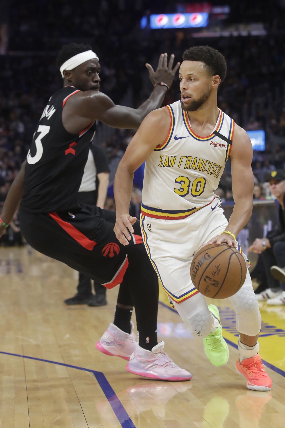 Warriors guard Stephen Curry slips past Raptors forward Pascal Siakam during the second half of a game March 5 at the Chase Center.