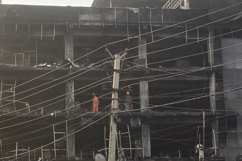 Rescuers work at the site of a fire in New Delhi, India, Saturday, May 14, 2022. A massive fire erupted Friday evening in a four-story commercial building in the Indian capital, killing more than two dozen people and leaving several others injured, the fire control room said. (AP Photo/Shonal Ganguly)
