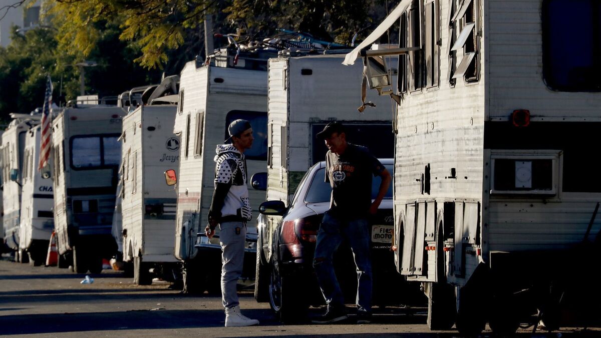 People stop and talk among a collection of RVs on West 94th Street near LAX in an area that had become a community. Police cleared and closed off the area in January.