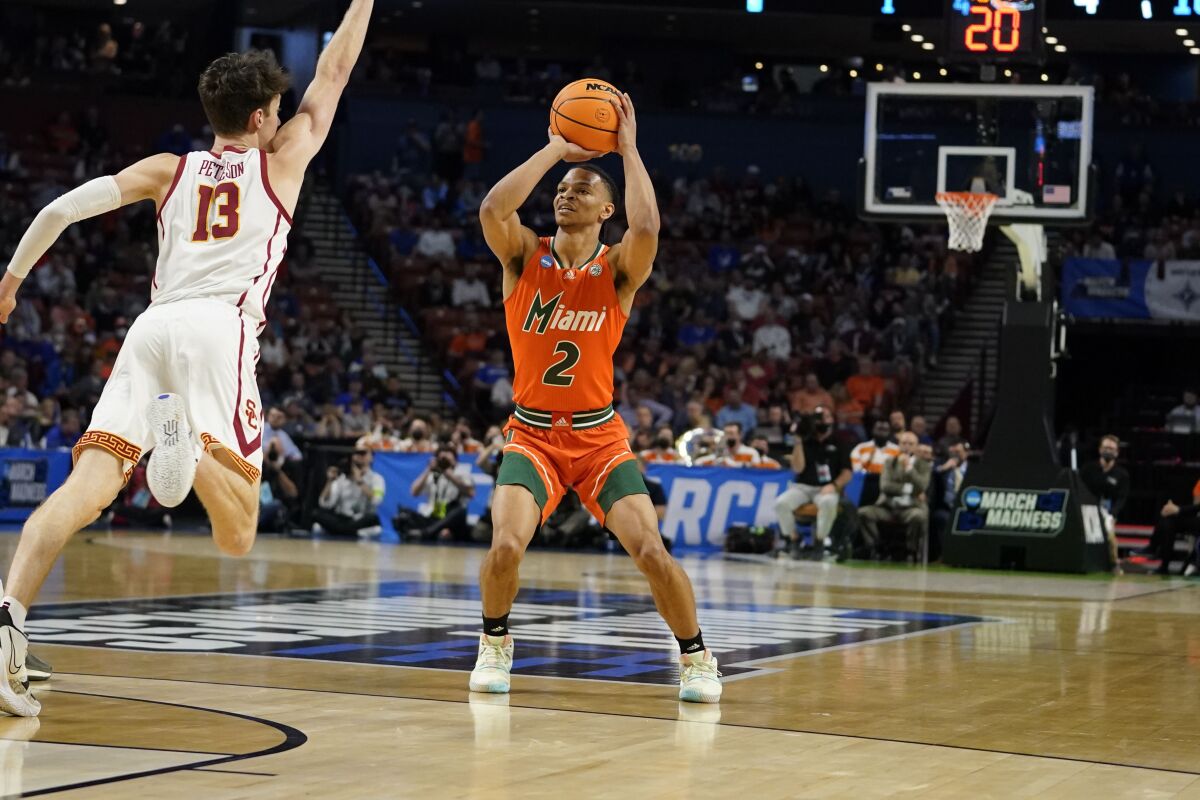 FILE - Miami's Isaiah Wong (2) shoots and scores during the first half of a college basketball game in the first round of the NCAA tournament against Southern California's Drew Peterson (13) March 18, 2022, in Greenville, S.C. An agent for Wong, a prominent college athlete finally said out loud what schools likely hear in private: Pay the player more, or he will transfer to a school that will. The demand made on behalf of Wong provided a rare glimpse into the way elite college sports have been transformed by student-athletes’ rights to earn money through endorsements. (AP Photo/Brynn Anderson, File)