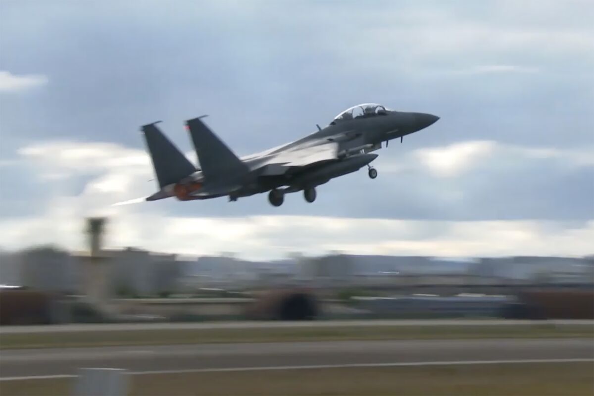 A military jet takes off from an airport runway