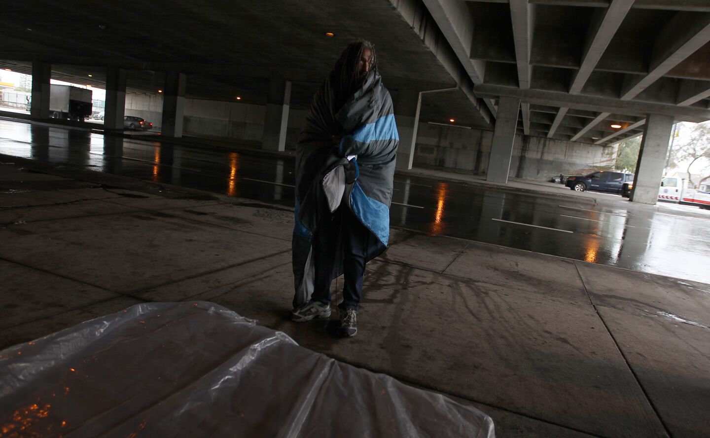 A homeless man seeks shelters beneath the 405 Freeway along Venice Boulevard as the first of several El Niño storms hit Southern California.