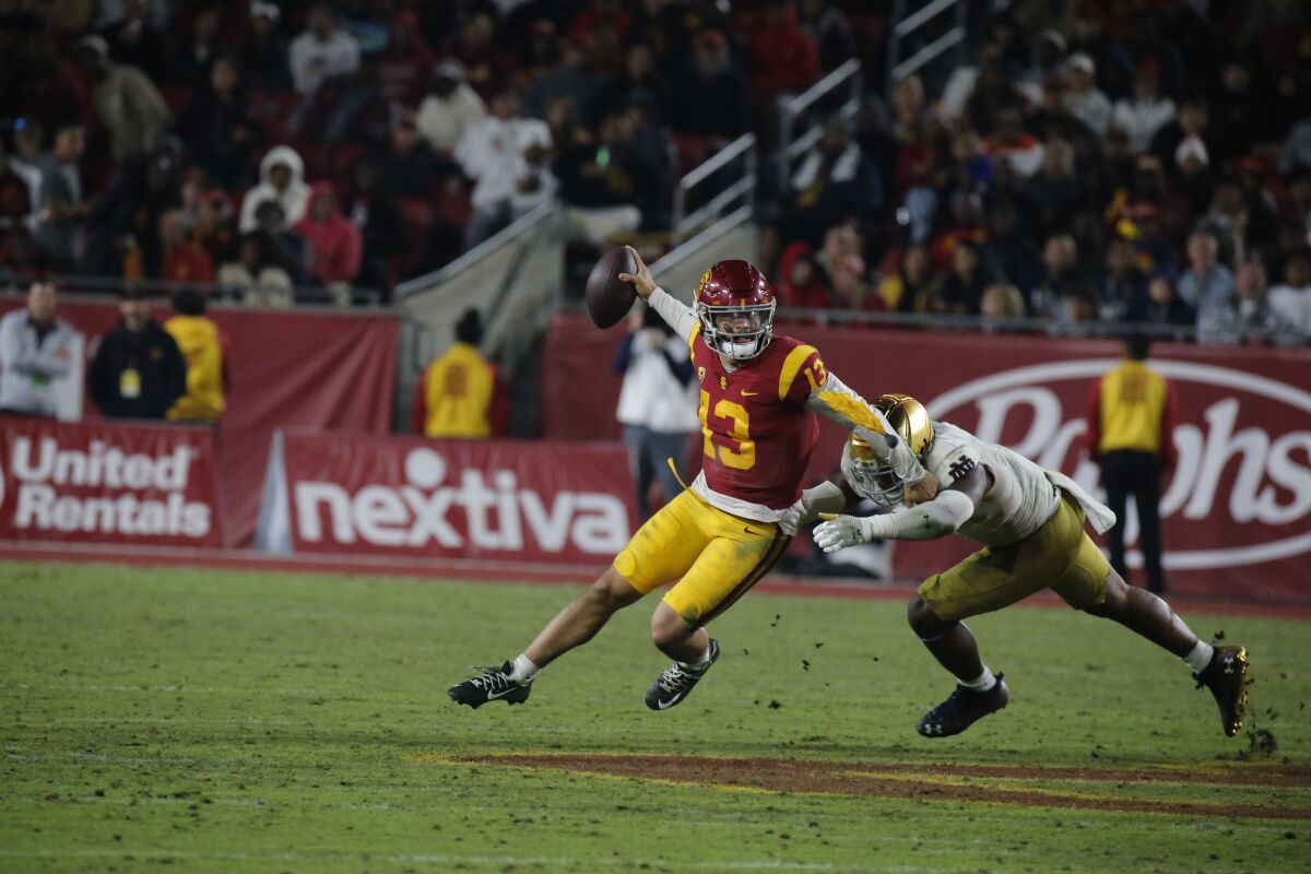 Le quart-arrière de l'USC Caleb Williams échappe au demi défensif de Notre Dame Justin Ademilola au quatrième quart le 26 novembre 2022. 