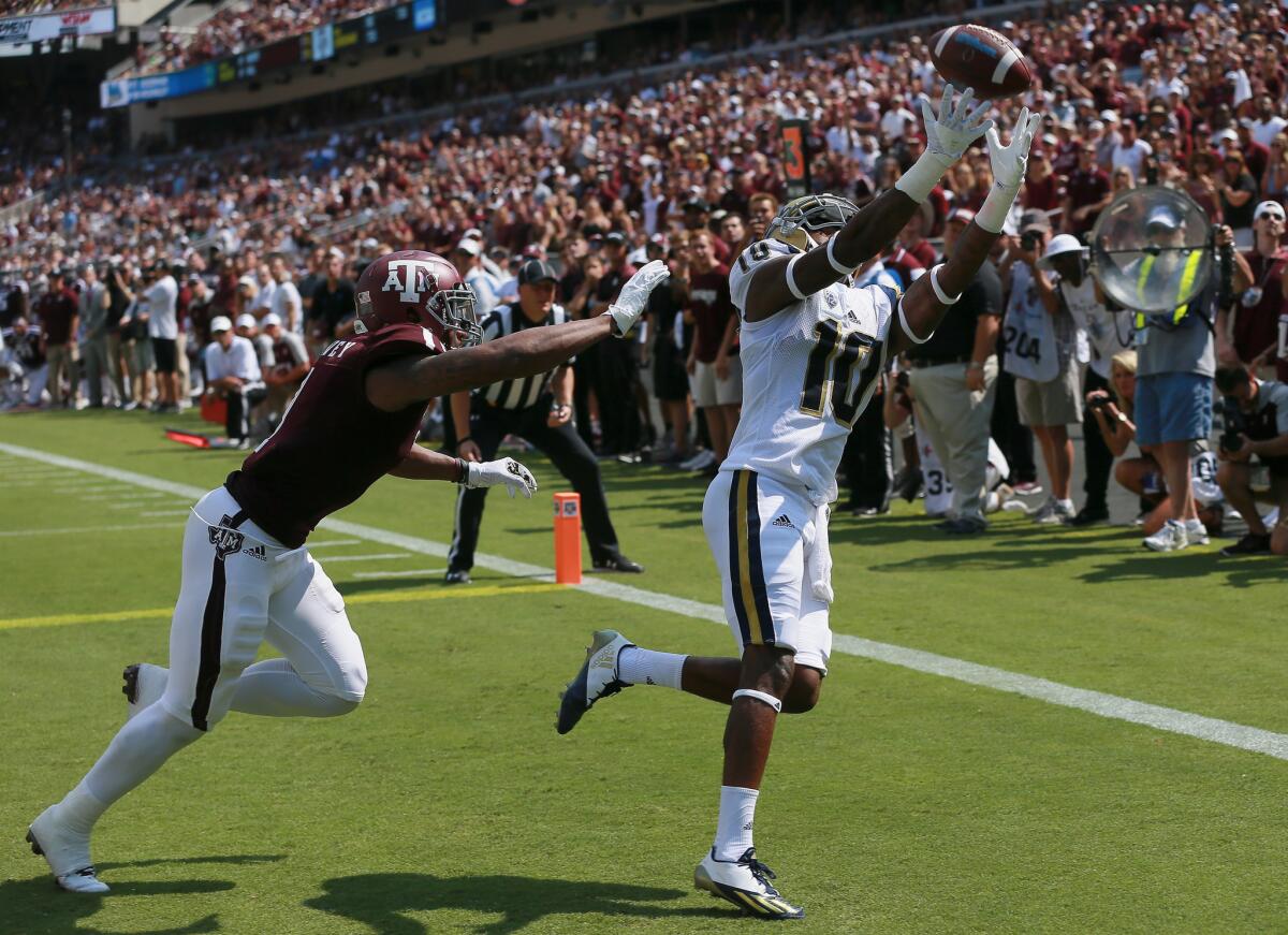 UCLA receiver Kenneth Walker III reaches toward a pass as Texas A&M's Nick Harvey defends during a game Saturday.