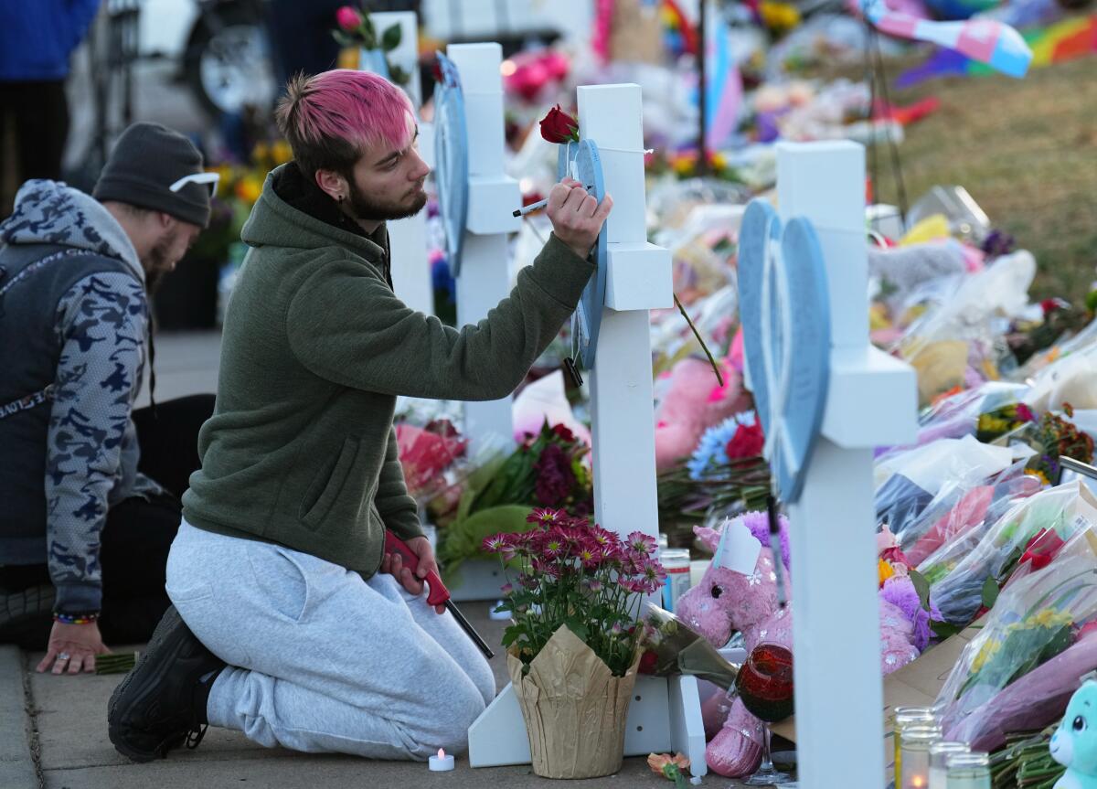 A man signs a cross at a makeshift tribute with a display of bouquets of flowers 