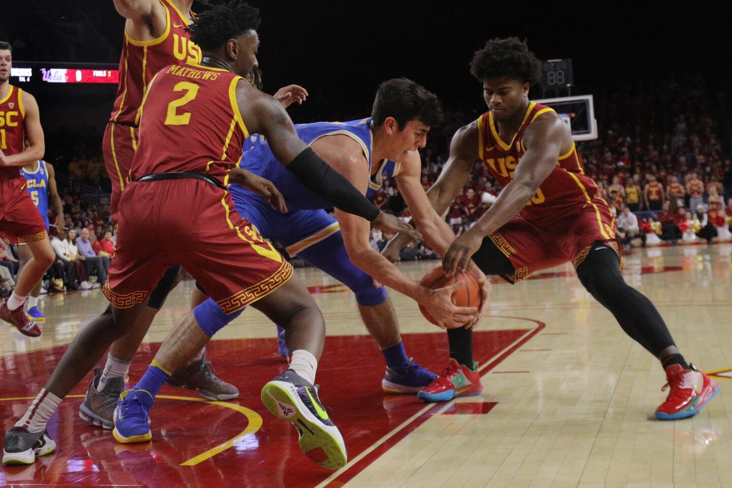 USC guards Jonah Mathews (2) and Ethan Anderson (20) try to rip the ball away from UCLA guard Jaime Jaquez Jr. during the first half of the Trojans' 54-52 victory over the Bruins at Galen Center on March 7, 2020.