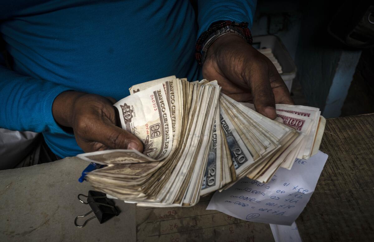 ARCHIVO - Un trabajador muestra un fajo de pesos cubanos en La Habana,
