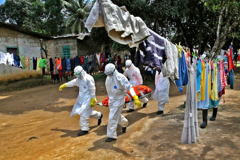 An Ebola burial team carries the body of a woman from a home in New Kru Town, a neighborhood of Monrovia, the Liberian capital.
