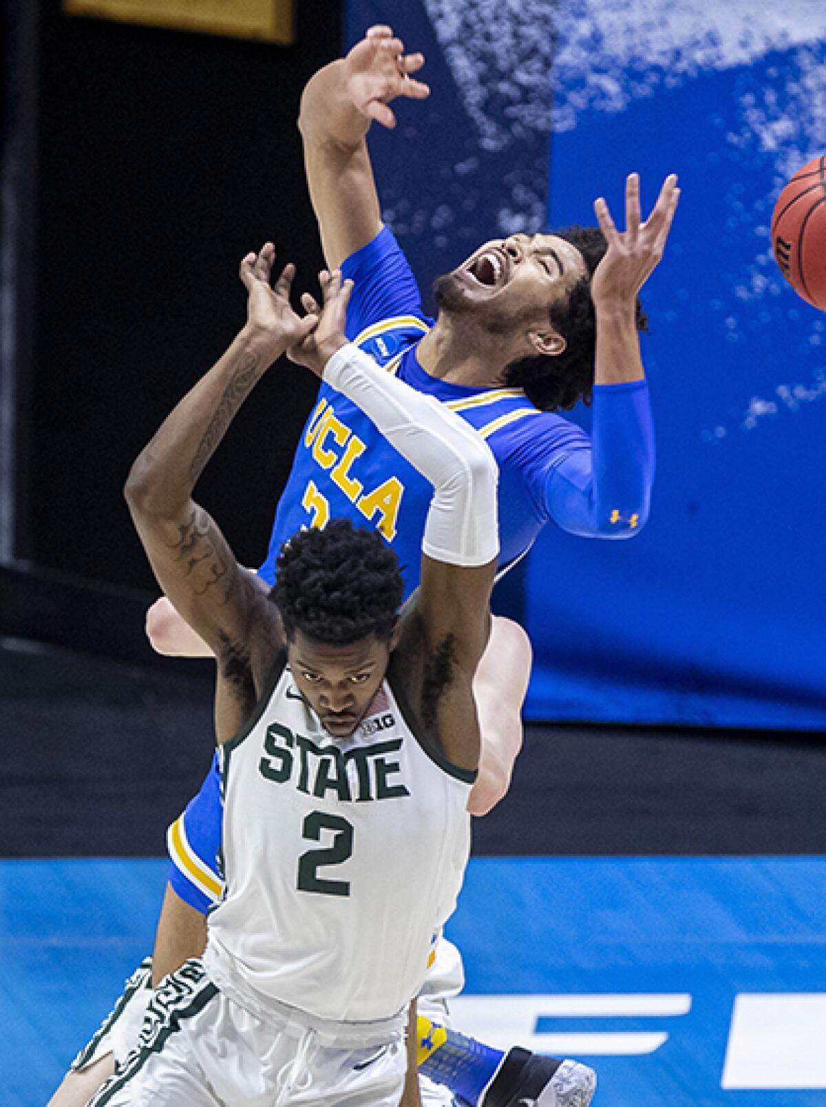 UCLA's Johnny Juzang battles Michigan State's Rocket Watts for a rebound.