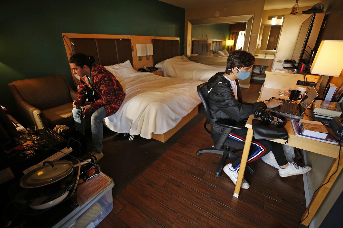 Two students are shown studying in a hotel room.