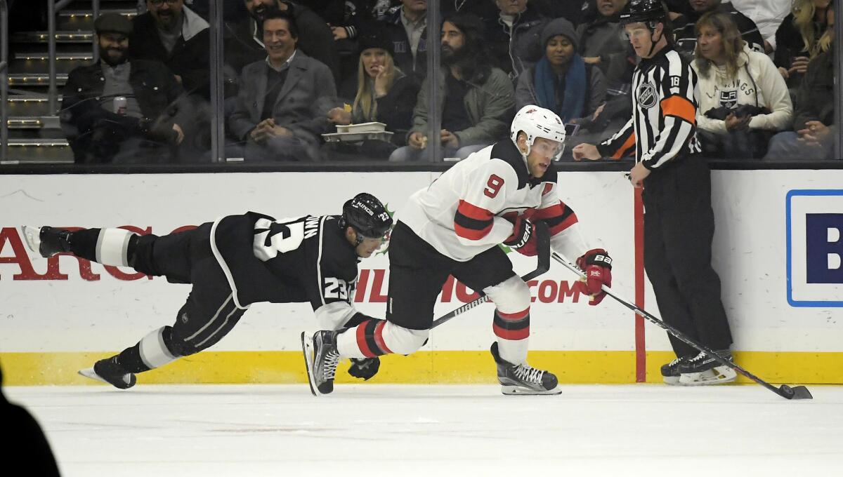 Kings right wing Dustin Brown, left, dives for the puck as New Jersey Devils left wing Taylor Hall takes it from him during the first period.