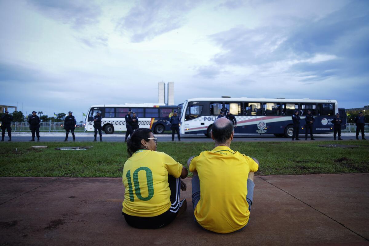 Una pareja de simpatizantes del expresidente Jair Bolsonaro observan el movimiento de agentes de la policía 