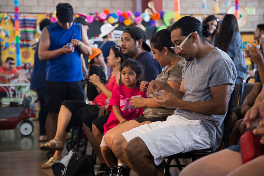 Seated audience members of kids and adults taste corn chips containing cricket from small plastic sampling cups.