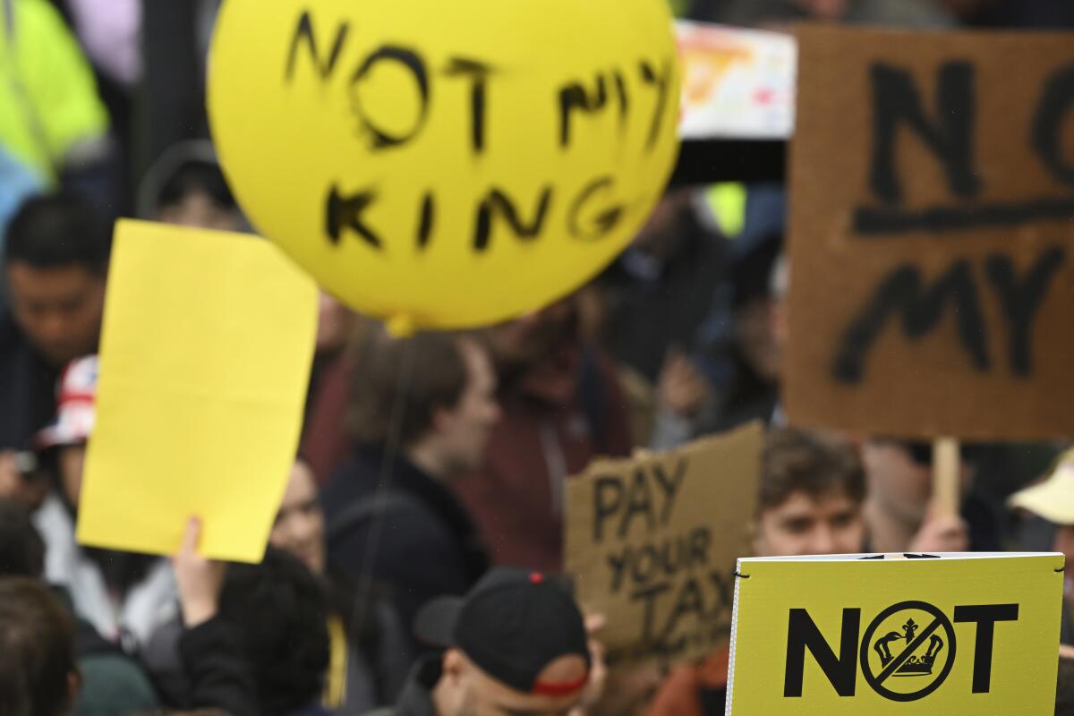 Protesters in London hold signs reading "Not My King" and "Pay Your Tax."