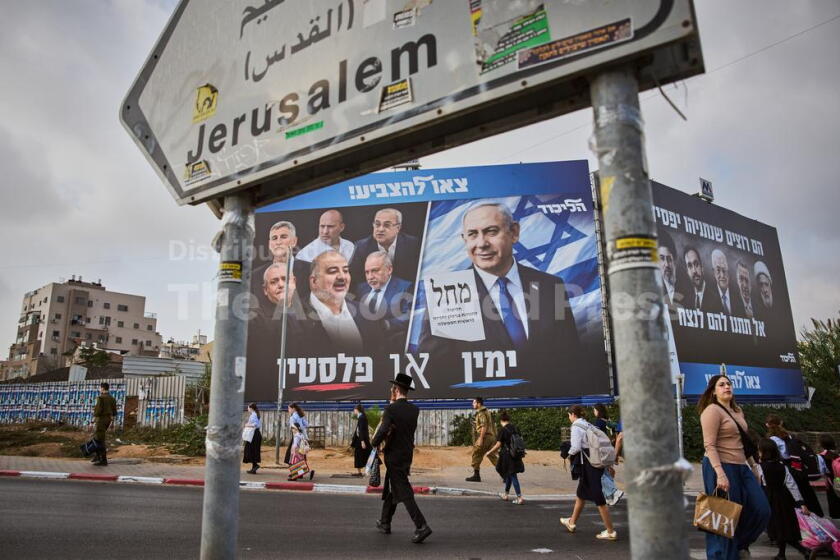 People walk past a Likud party campaign billboard featuring Israeli Prime Minister Benjamin Netanyahu