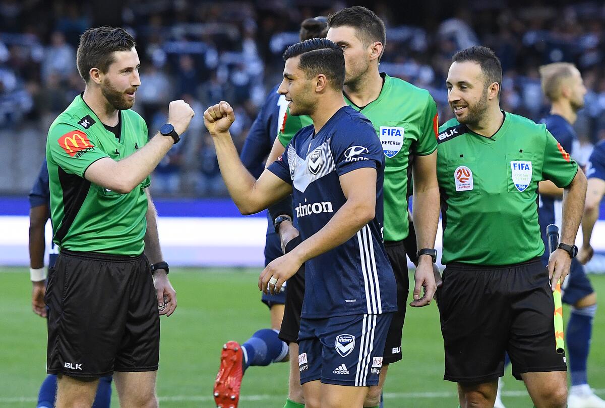 Players and officials fist bump rather than shake hands before an Australian soccer league match on March 7.