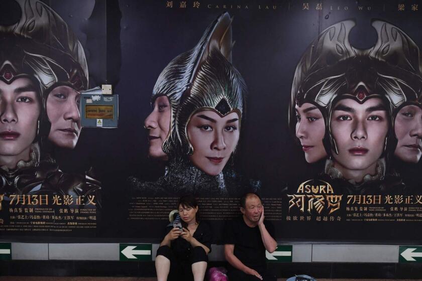 A man and woman rest in front of posters for the movie Asura at a subway station in Beijing on July 17, 2018. Pulled from cinemas after its opening weekend, China's most expensive domestically made film has become a flop of historic proportions, bringing in just 7.3 million USD despite a reported budget of over 110 million USD. / AFP PHOTO / GREG BAKERGREG BAKER/AFP/Getty Images ** OUTS - ELSENT, FPG, CM - OUTS * NM, PH, VA if sourced by CT, LA or MoD **