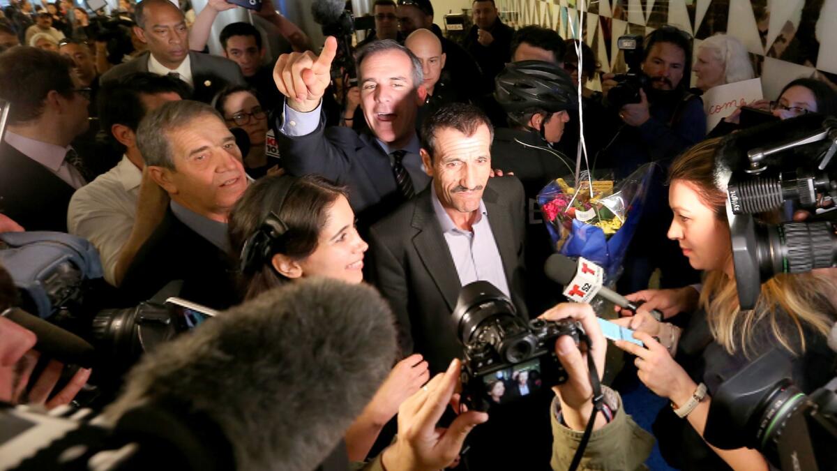 Ali Vayeghan, center, an Iranian citizen with a valid U.S. visa, is swarmed by the media as he is escorted through LAX by L.A. Mayor Eric Garcetti after his arrival.
