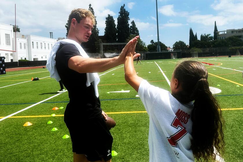 Former USC quarterback Miller Moss high fives a participant at his football camp at Beverly Hills High School.