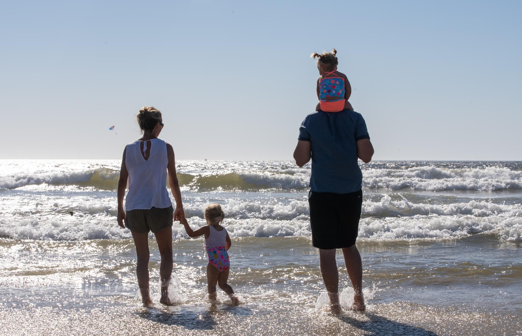 Two parents holding their two children on a coastline