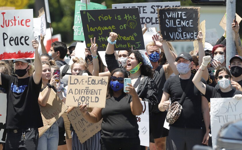 Demonstrators chant and hold up signs during a Black Lives Matter protest in Newport Beach on June 3.