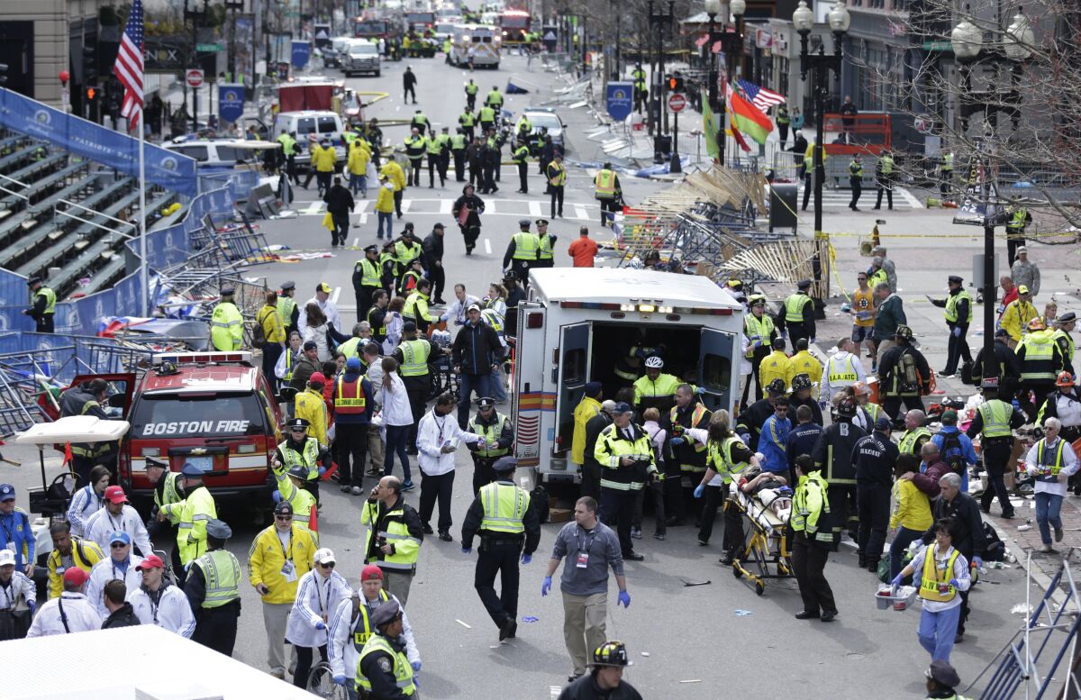 Emergency workers aid injured people at the finish line of the 2013 Boston Marathon following two explosions in Boston. 