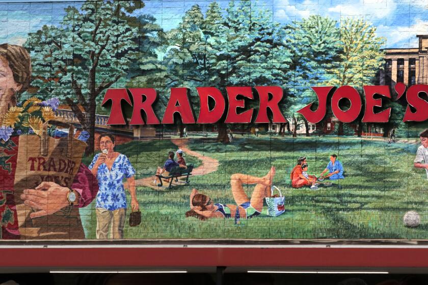 FILE - The Trader Joe's logo hangs on a mural, Aug. 13, 2019, in Cambridge, Mass. Trader Joe's recently upped the price to 23 cents for a single banana, marking a 4-cent increase from the grocer's previous going rate for the fruit that remained unchanged for over 20 years. (AP Photo/Charles Krupa, File)