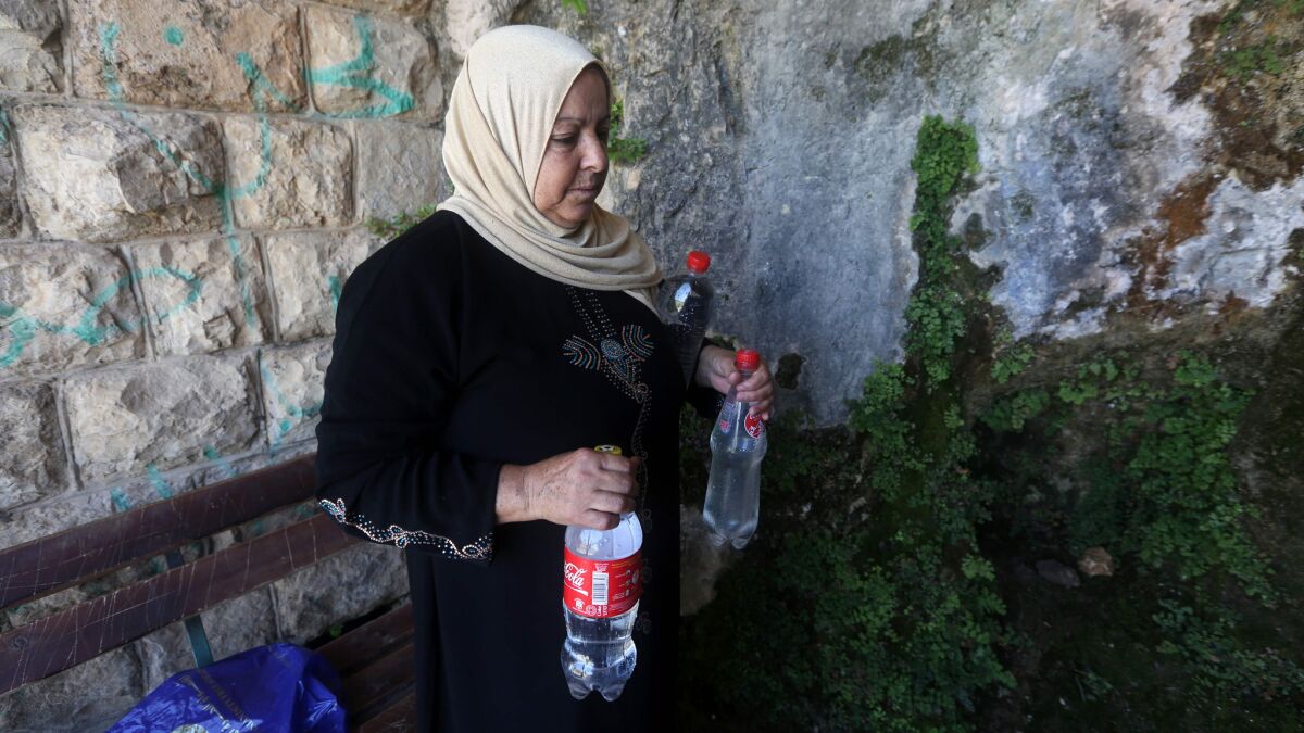 A member of the Salim family carries bottles filled with spring water on June 23 in Salfit, north of Ramallah, where some of the West Bank village's inhabitants have been without water for days.