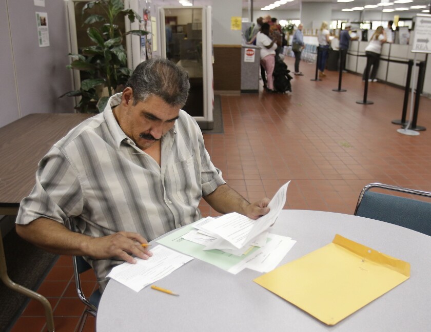 Luis Rodriguez, who has been out of work for a year, fills out forms at the EDD's Sacramento office.