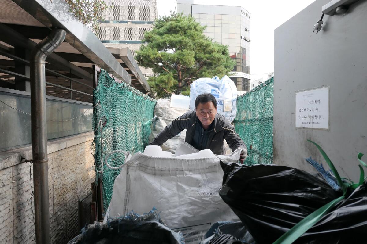 Lee Yong-gi, 62, gathers up bags of recyclables in Seoul.