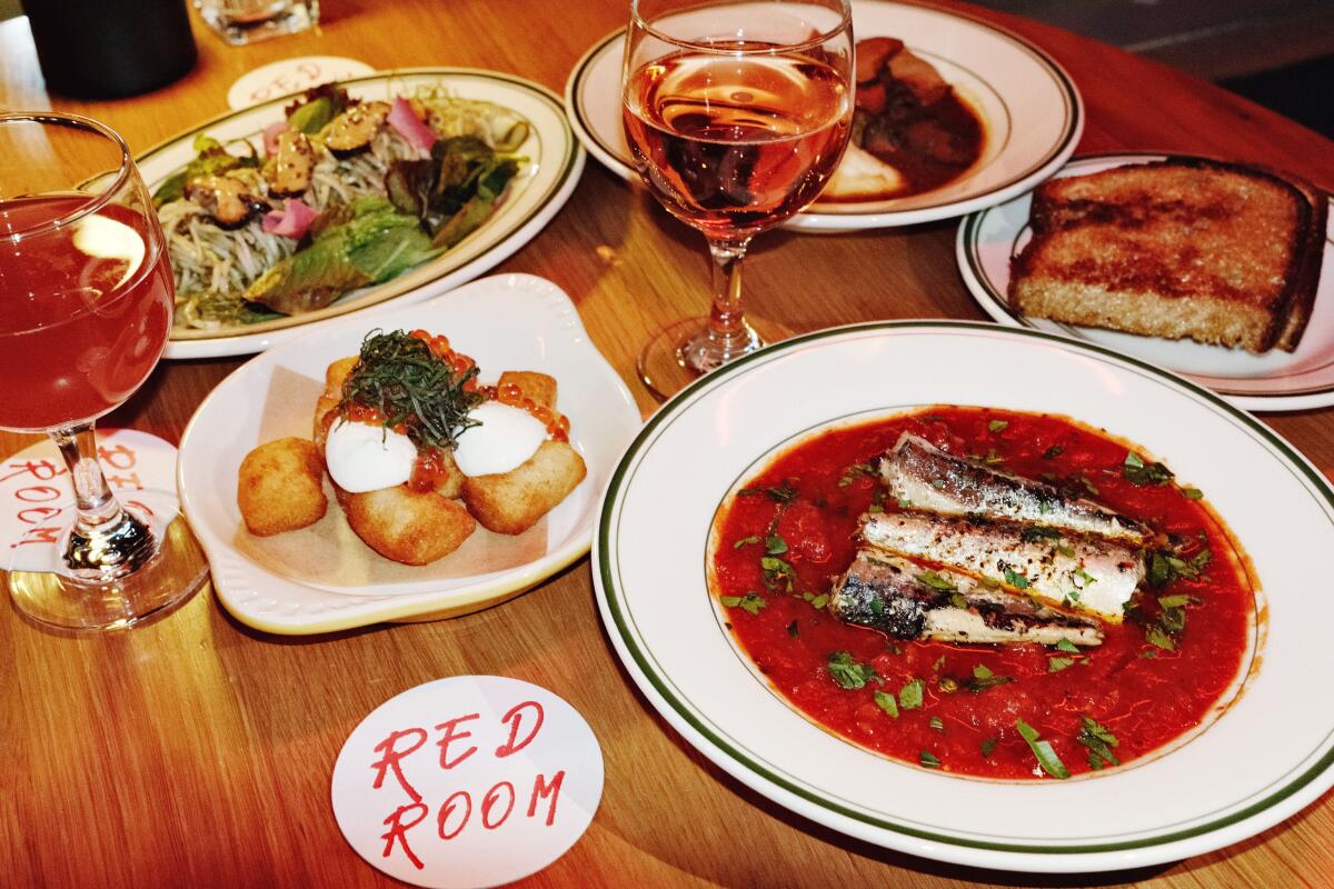 A spread of Korean small plates with two glasses of wine from Red Room in Koreatown.