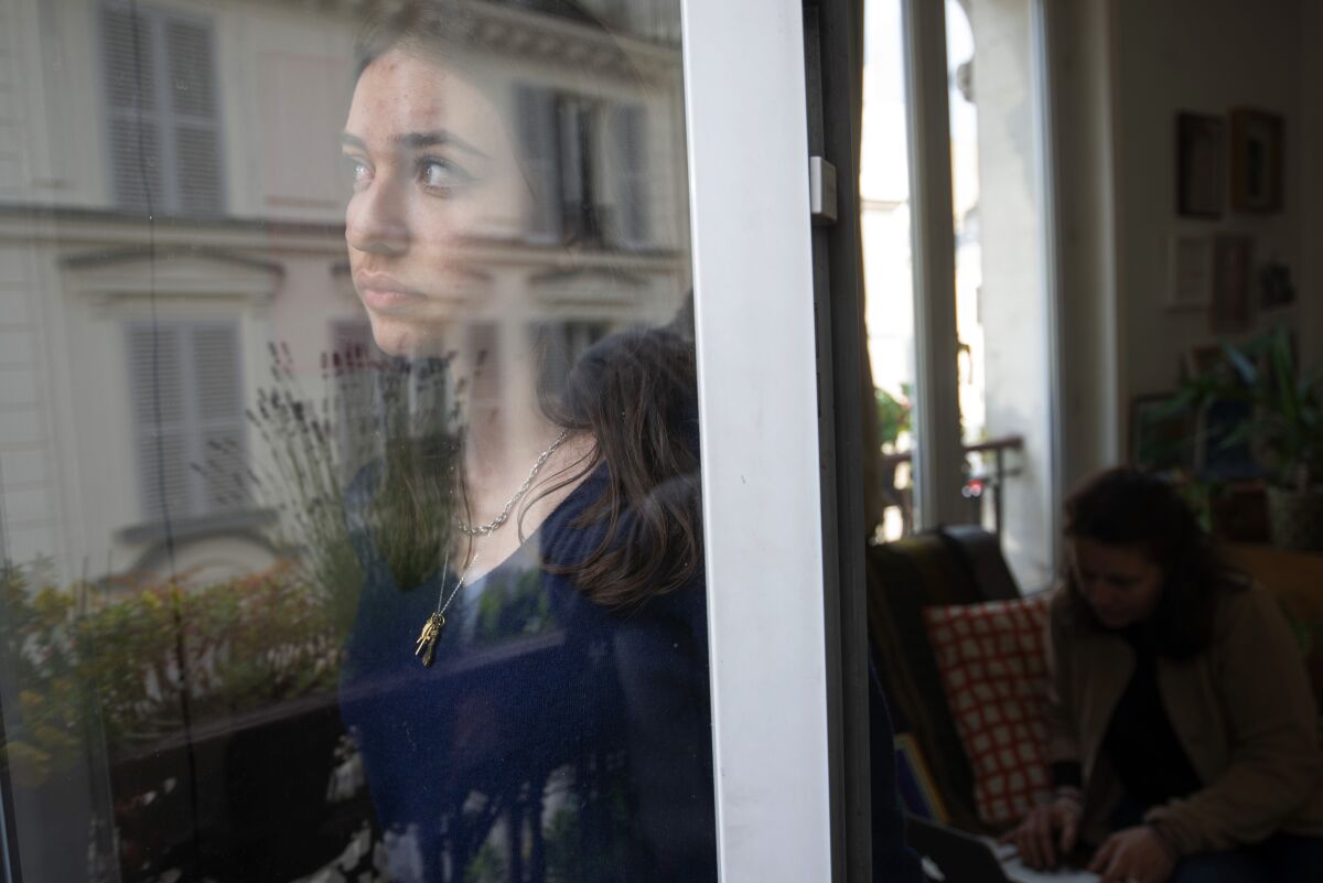 Anais Bulcao, 17, stares through a window of her family apartment in Montmartre, where she lives with her parents, on May 21, 2021. Also living with them again is her elder sister Livia, who was traveling when the pandemic struck and was repatriated to Paris. Anais says she already has trouble remembering the months they spent together in lockdown. "Looking back, it seems like the lockdown only lasted a day," she says. (AP Photo/ Joao Luiz Bulcao).
