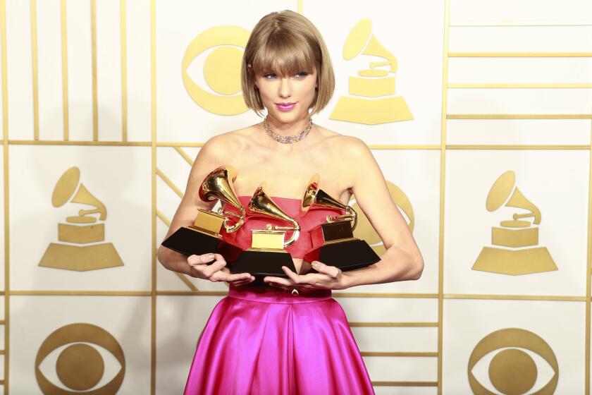 Taylor Swift holding three Grammys trophies