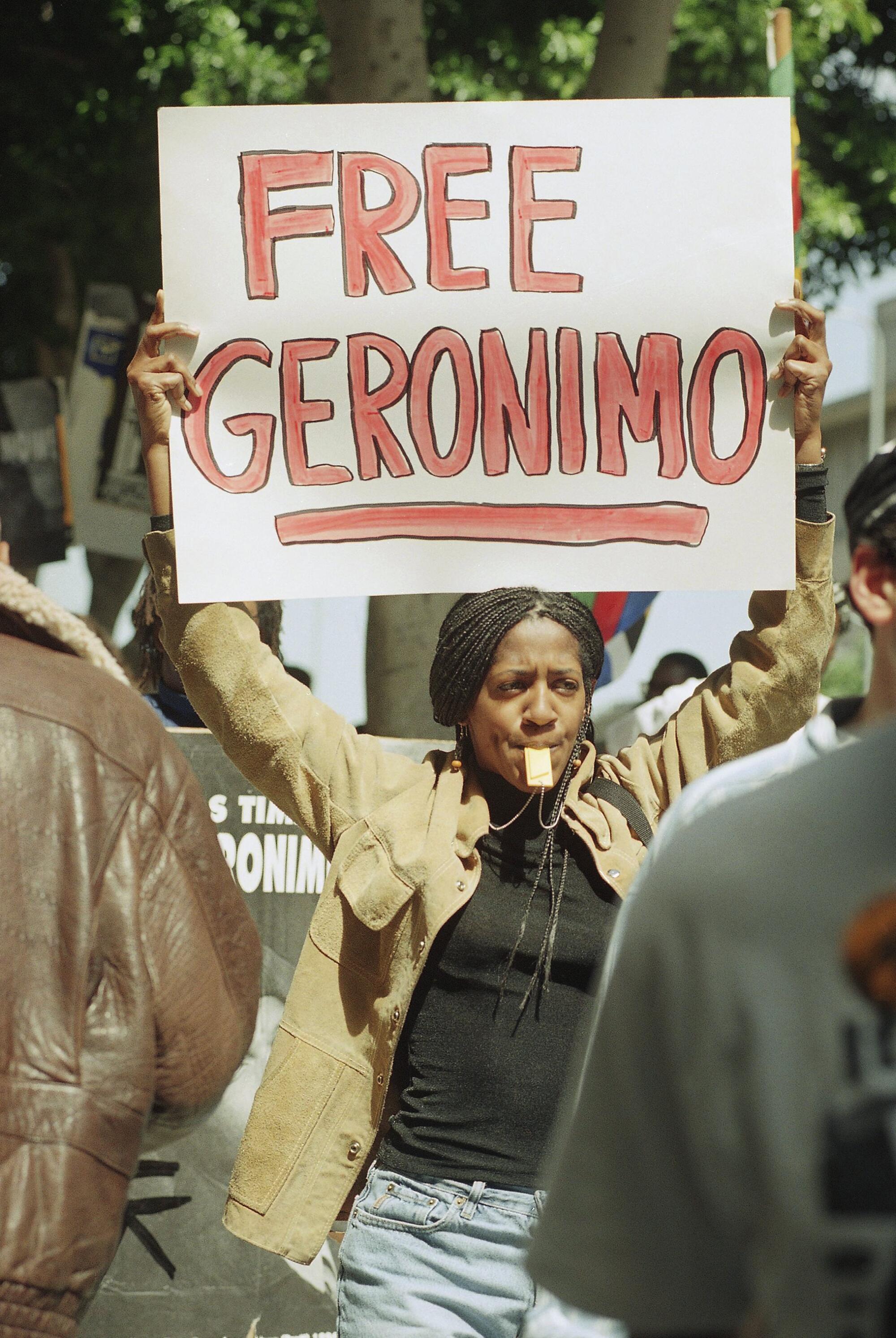 Uma mulher que segura um pequeno sinal e palavras 'sem geronmimo' escrito no vermelho