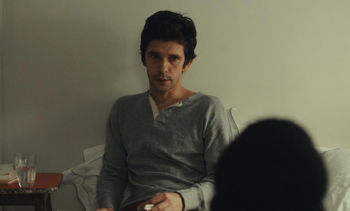 A man in a gray shirt sits in bed