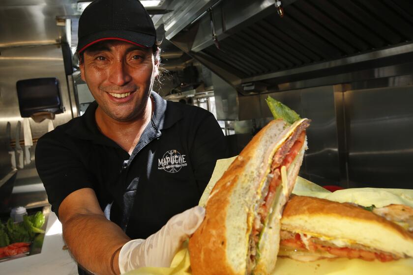 LOS ANGELES, CA-JULY 26, 2017: Carlos Puga, is photographed with a Lomito (steak sandwich), one of the items on the menu of the Argentinian food truck, Mapuche, that he runs on July 26, 2017. (Mel Melcon/Los Angeles Times)