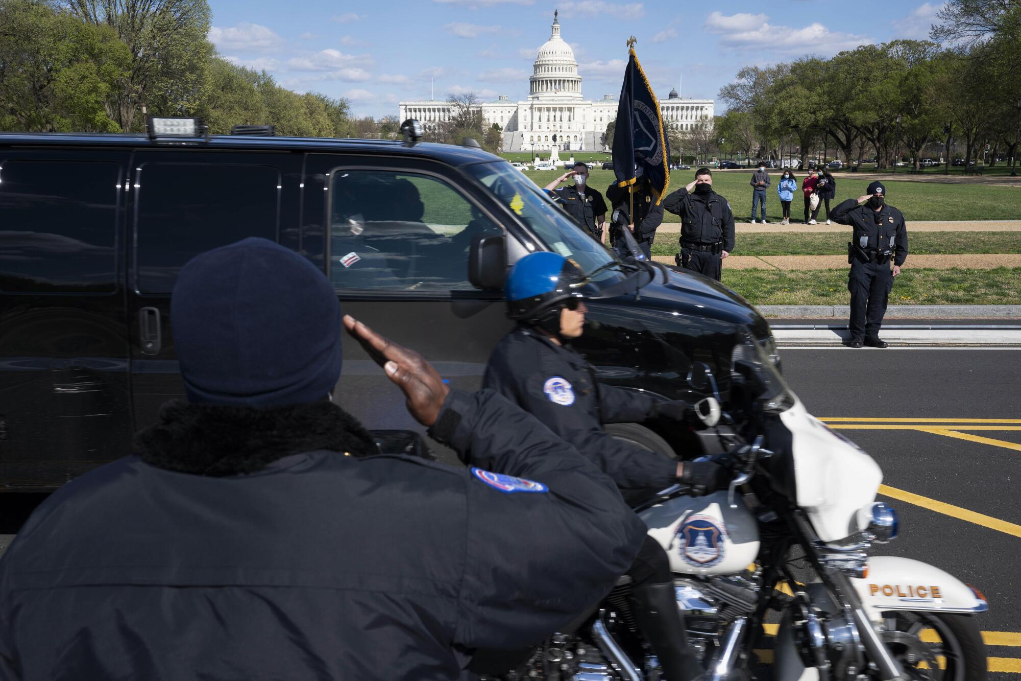 With the U.S. Capitol in the background, U.S. Capitol Police officers salute as procession goes by.