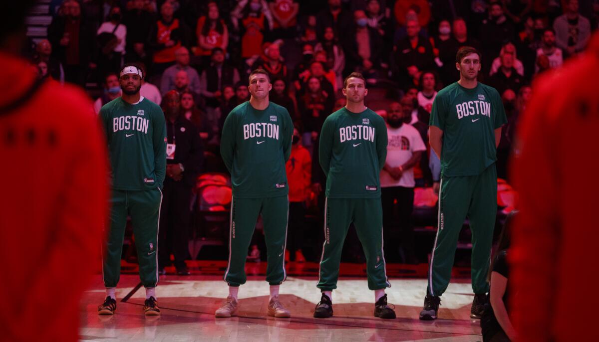 Boston forward Matt Ryan, second from left, stands for the national anthem before an NBA game last March.