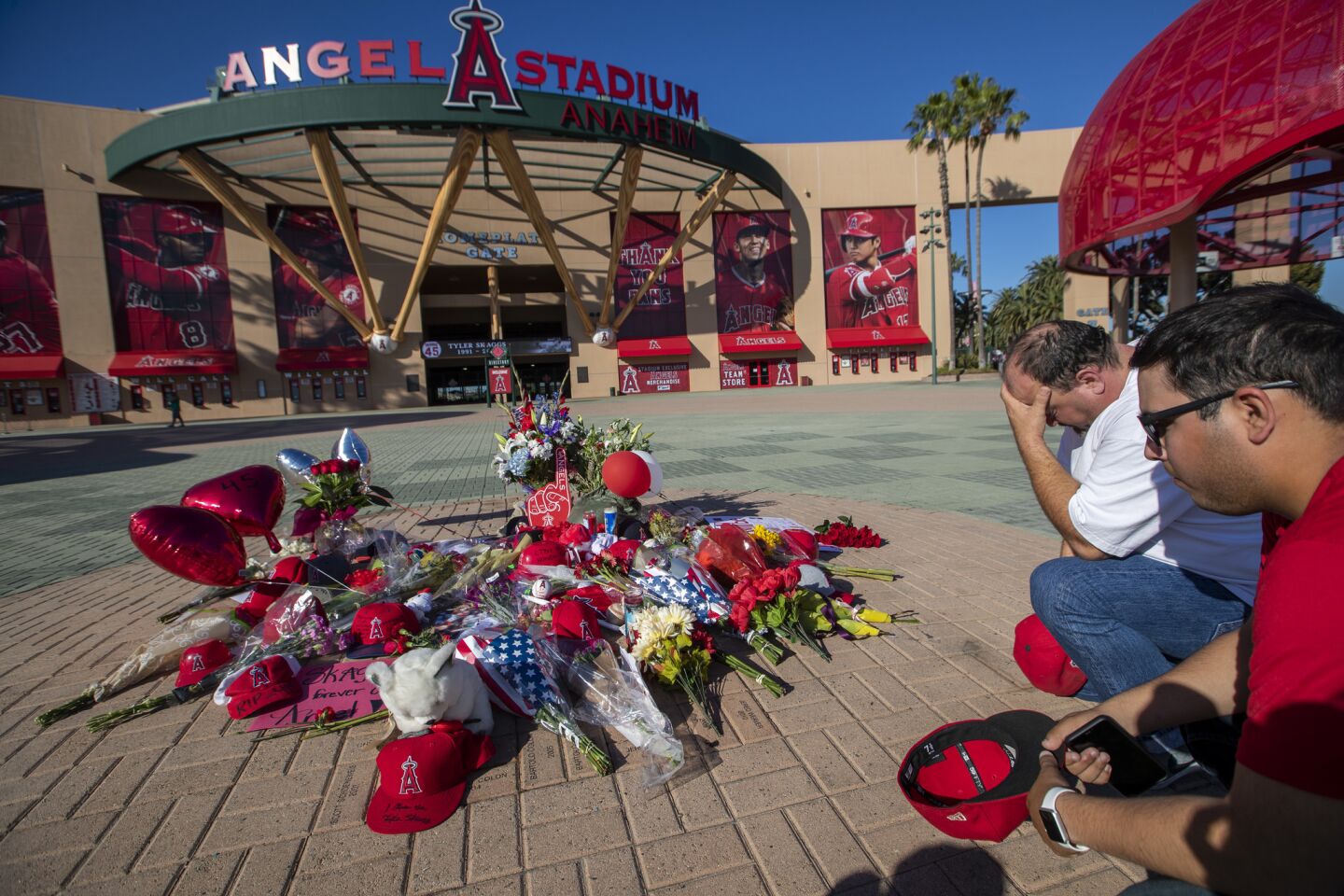 Karl Arriola, left, and his son, Jonathan, of Santa Ana, spend a quiet moment at a growing memorial for Tyler Skaggs at Angel Stadium.