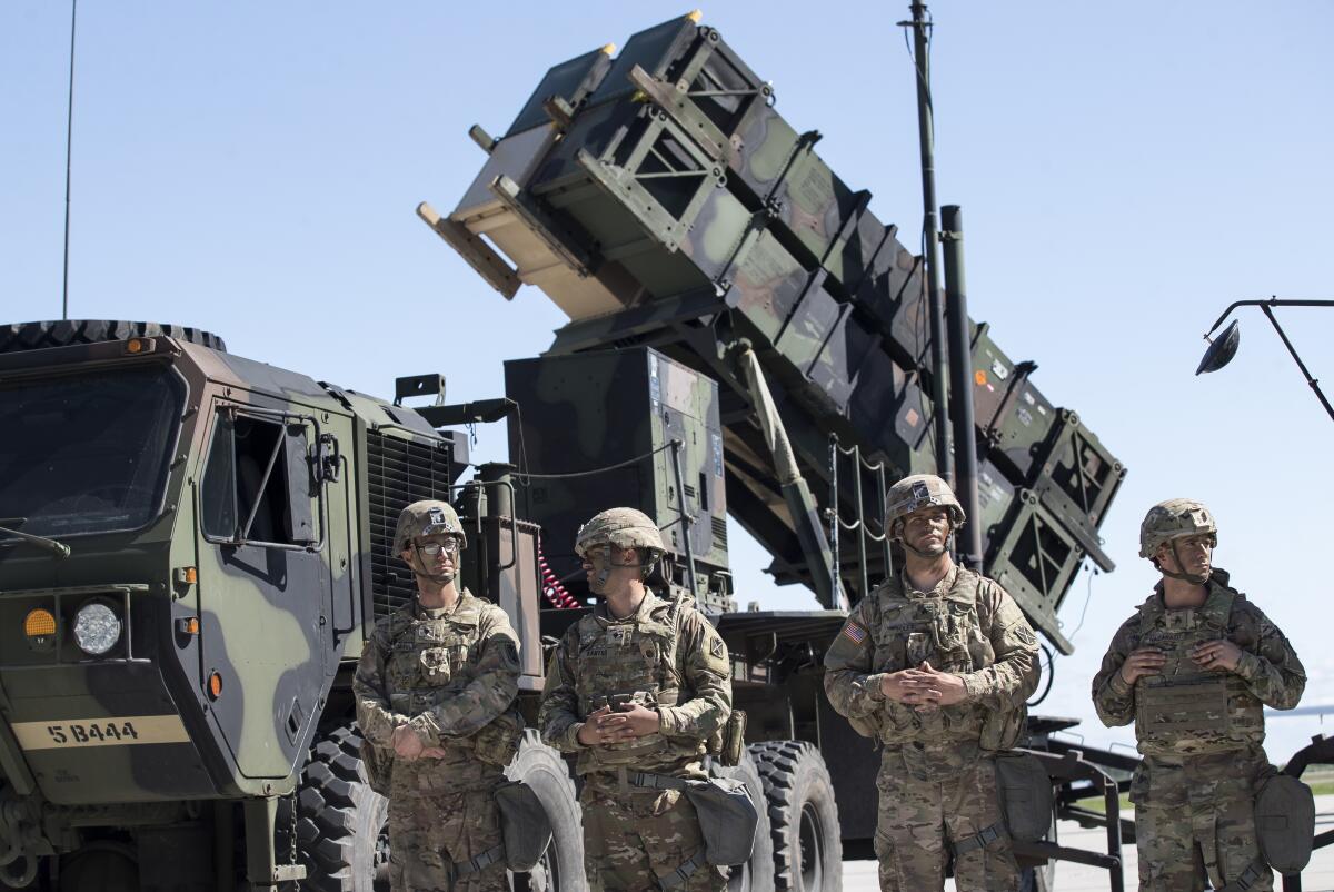 U.S. military members stand next to a Patriot surface-to-air missile battery.