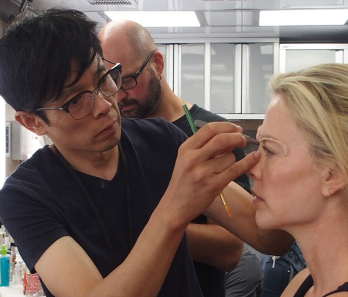Charlize Theron gets her eyelids worked on by prosthetic designer Kazu Hiro to transform into Fox News anchor Megyn Kelly for “Bombshell.” Hiro, Anne Morgan and Vivian Baker have been nominated for an Oscar for best achievement in makeup and hairstyling for their work on the film.