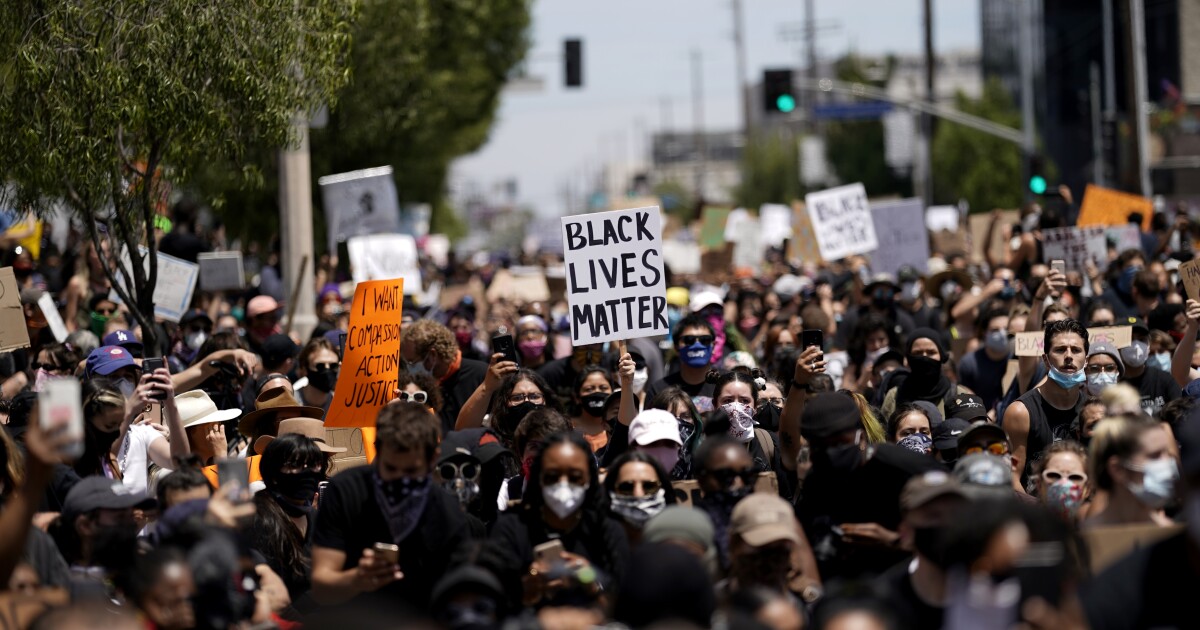 People holding up signs at a gathering set up by groups Black Lives Matter Los Angeles and Build Power at Pan Pacific Park.