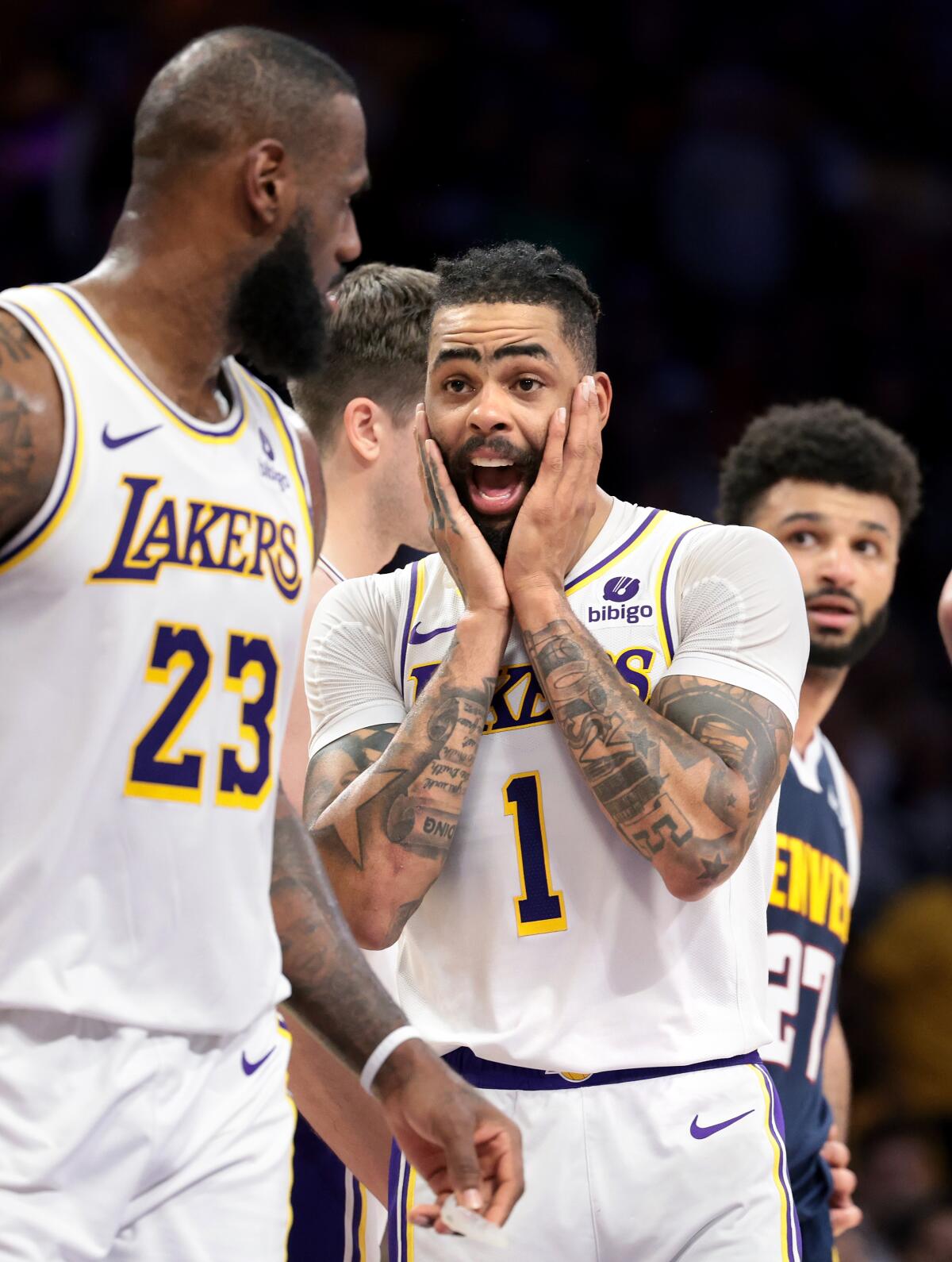 Lakers guard D'Angelo Russell holds his face with both hands in exclamation while talking to LeBron James during Game 4.