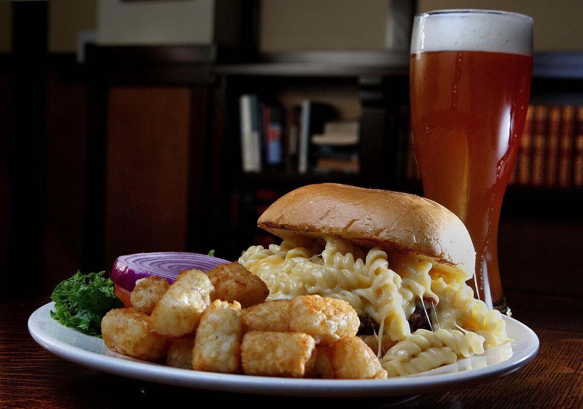 The Mac Attack, a $13.00 favorite at the Story Tavern, is a 100% half-pound juicy beef patty topped with classic macaroni & cheese, thick sliced applewood bacon with melted Swiss cheese served on a potato bun in Burbank on Friday, August 9, 2013. The beer is Hacker Pschorr Hefeweizen.