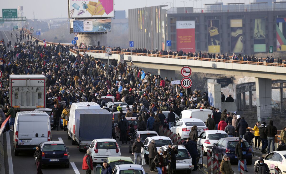 Protesters stand on the highway during a protest in Belgrade, Serbia, Saturday, Dec. 4, 2021. Thousands of protesters have gathered in Belgrade and other Serbian towns and villages to block roads and bridges despite police warnings and an intimidation campaign launched by authorities against the participants. Thousands of protesters have gathered in Belgrade and other Serbian towns and villages to block roads and bridges despite police warnings and an intimidation campaign launched by authorities against the participants. (AP Photo/Darko Vojinovic)