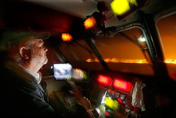 Martin Maher maneuvers his boat through Los Angeles Harbor in the early morning darkness. Maher's job is to deliver port pilots to incoming container ships.
